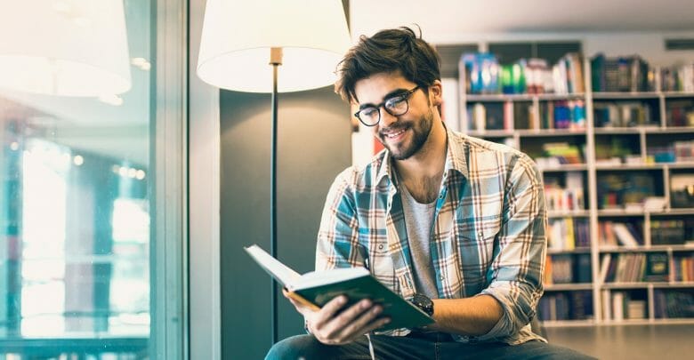 Young man reading book in the library